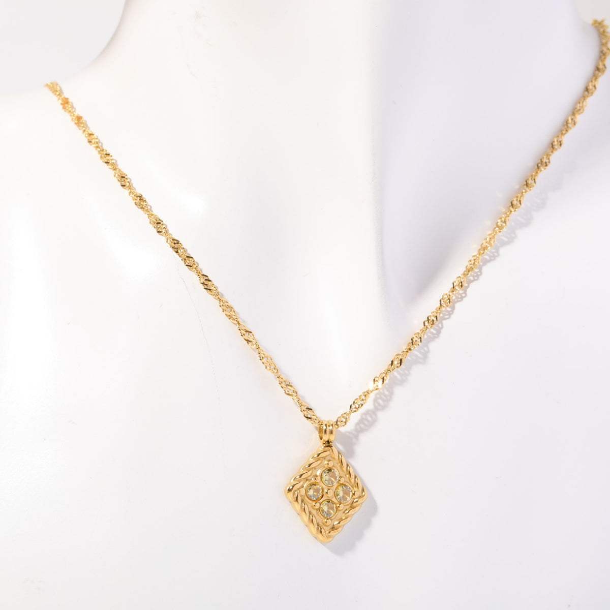 Birthstone necklace with four pale yellow crystals in a twisted gold rope frame, worn on a display bust