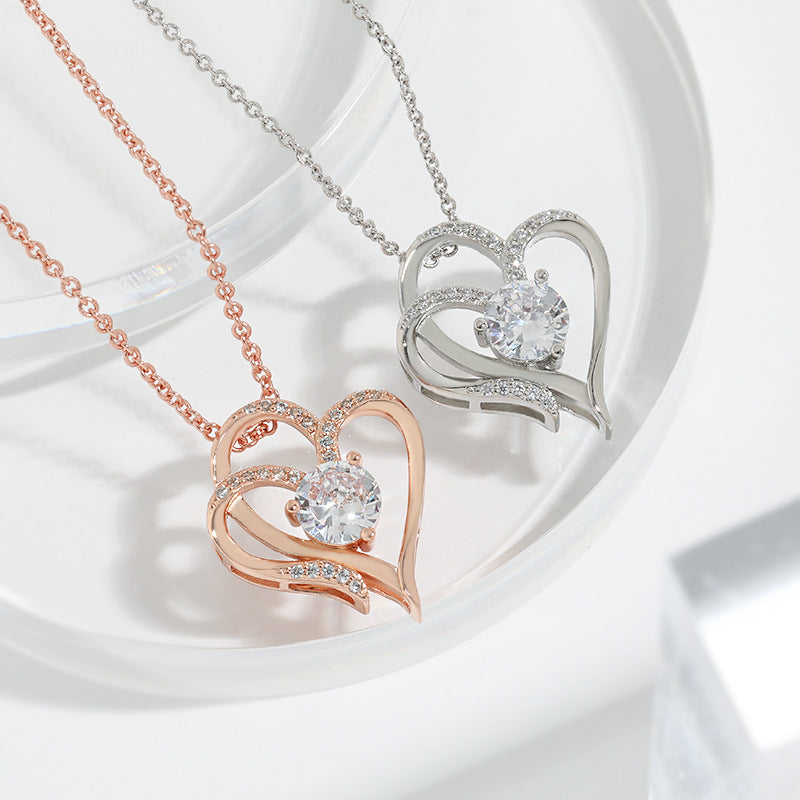 Rose gold and silver double heart necklaces shown together, chains coiled beside the pendants
