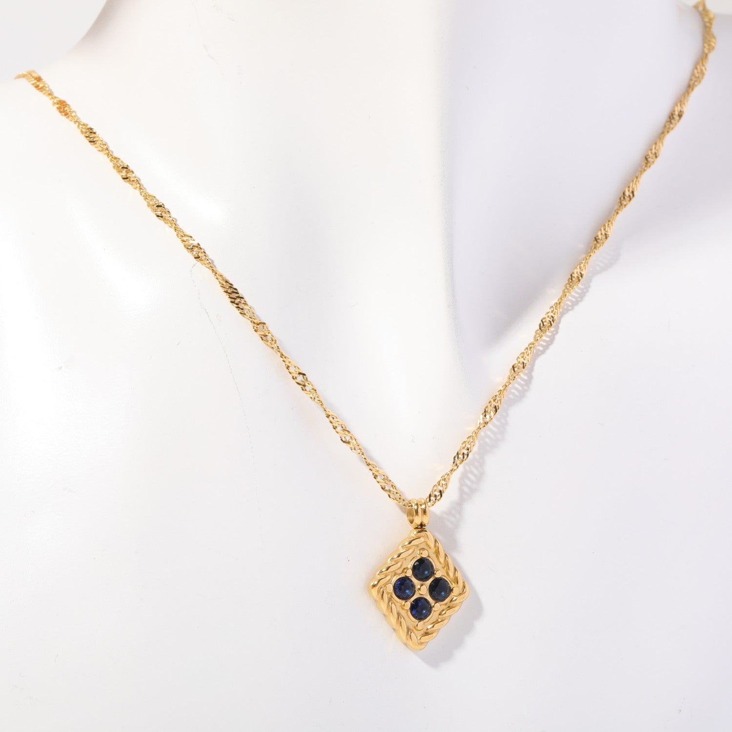 Birthstone necklace with four deep blue crystals in a twisted gold rope frame, worn on a display bust