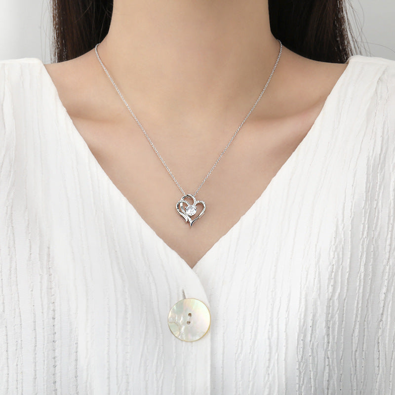 Woman wearing the silver double heart necklace, pendant resting just below the collarbone on an open white collar