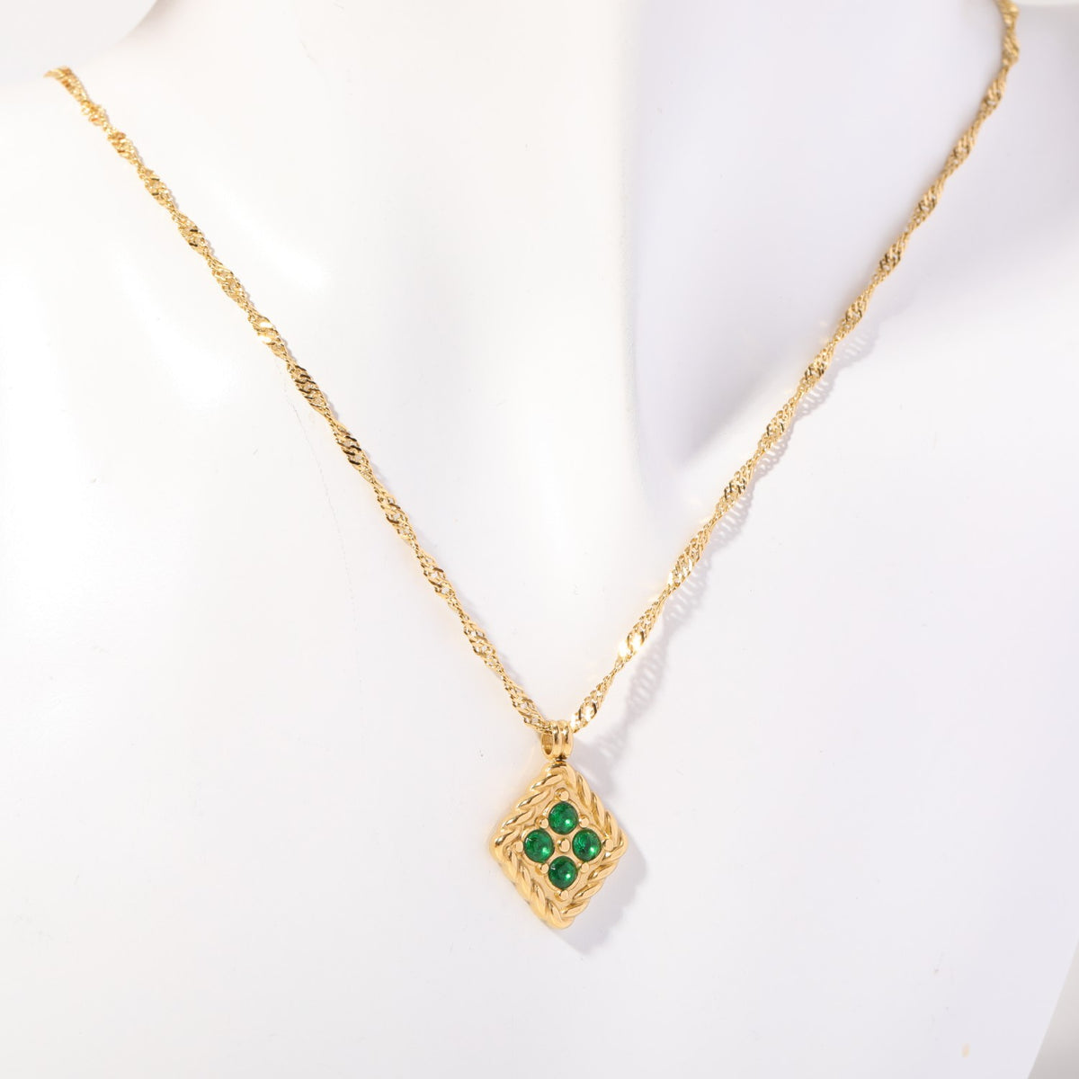 Birthstone necklace with four green crystals in a twisted gold rope frame, worn on a display bust