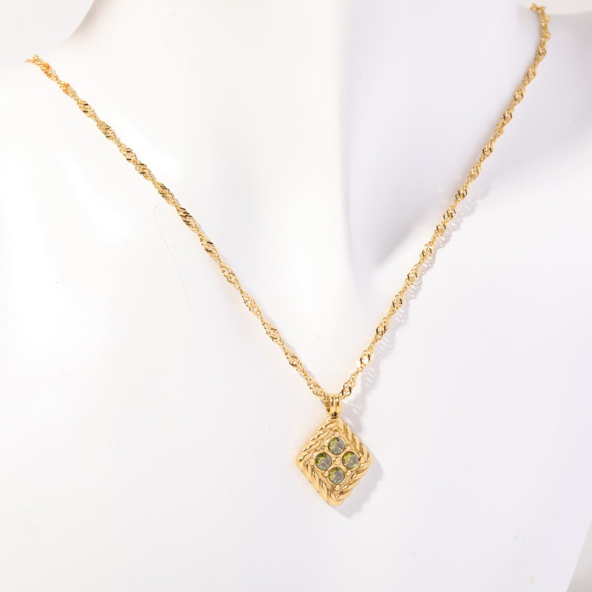 Birthstone necklace with four pale crystals in a twisted gold rope frame, worn on a display bust