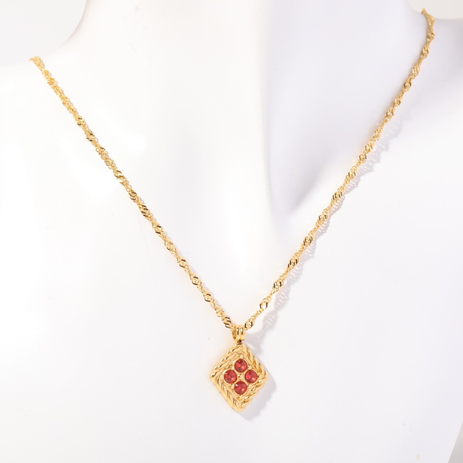 Birthstone necklace with four warm red crystals in a twisted gold rope frame, worn on a display bust