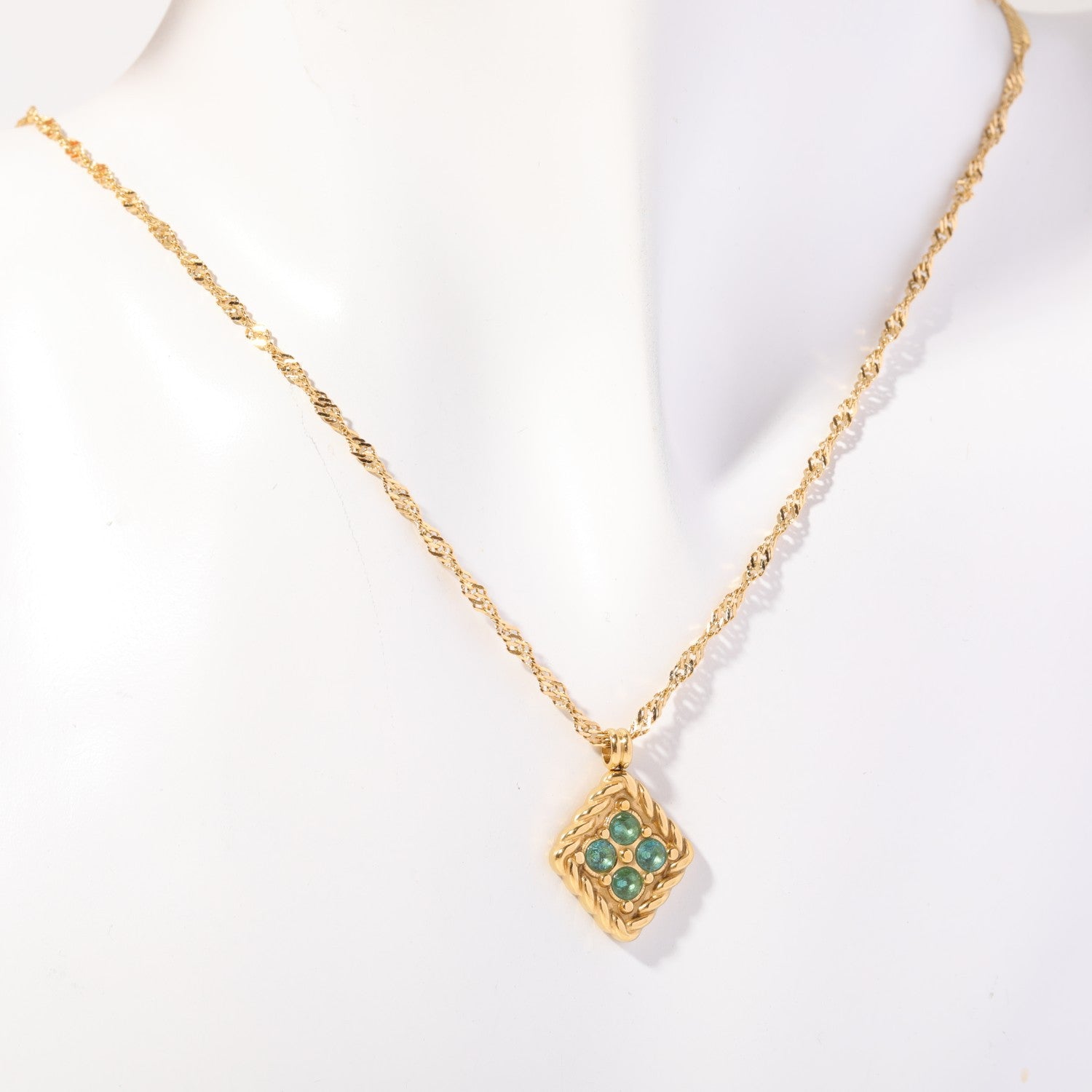 Birthstone necklace with four teal crystals in a twisted gold rope frame, worn on a display bust