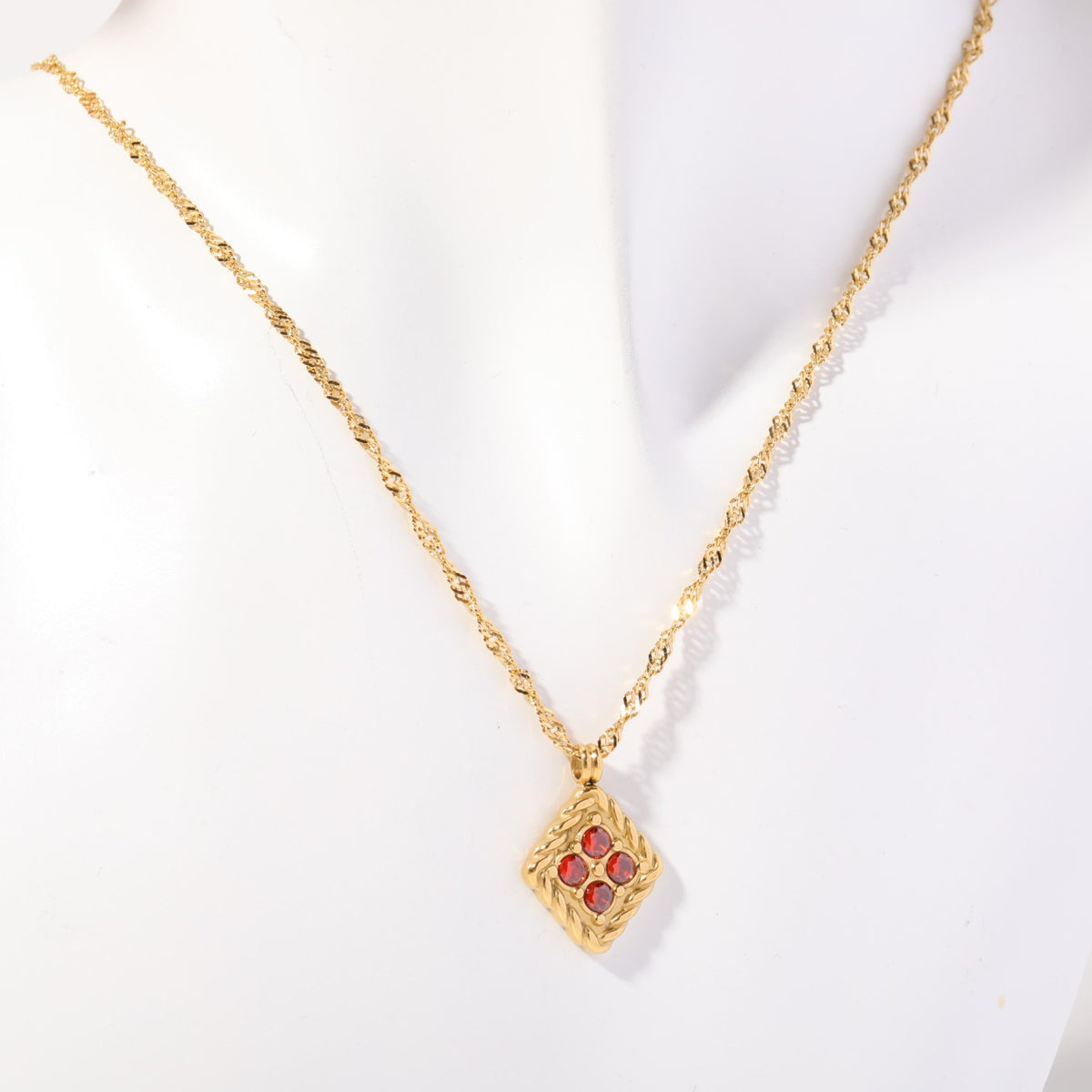Birthstone necklace with four red crystals in a twisted gold rope frame, worn on a display bust