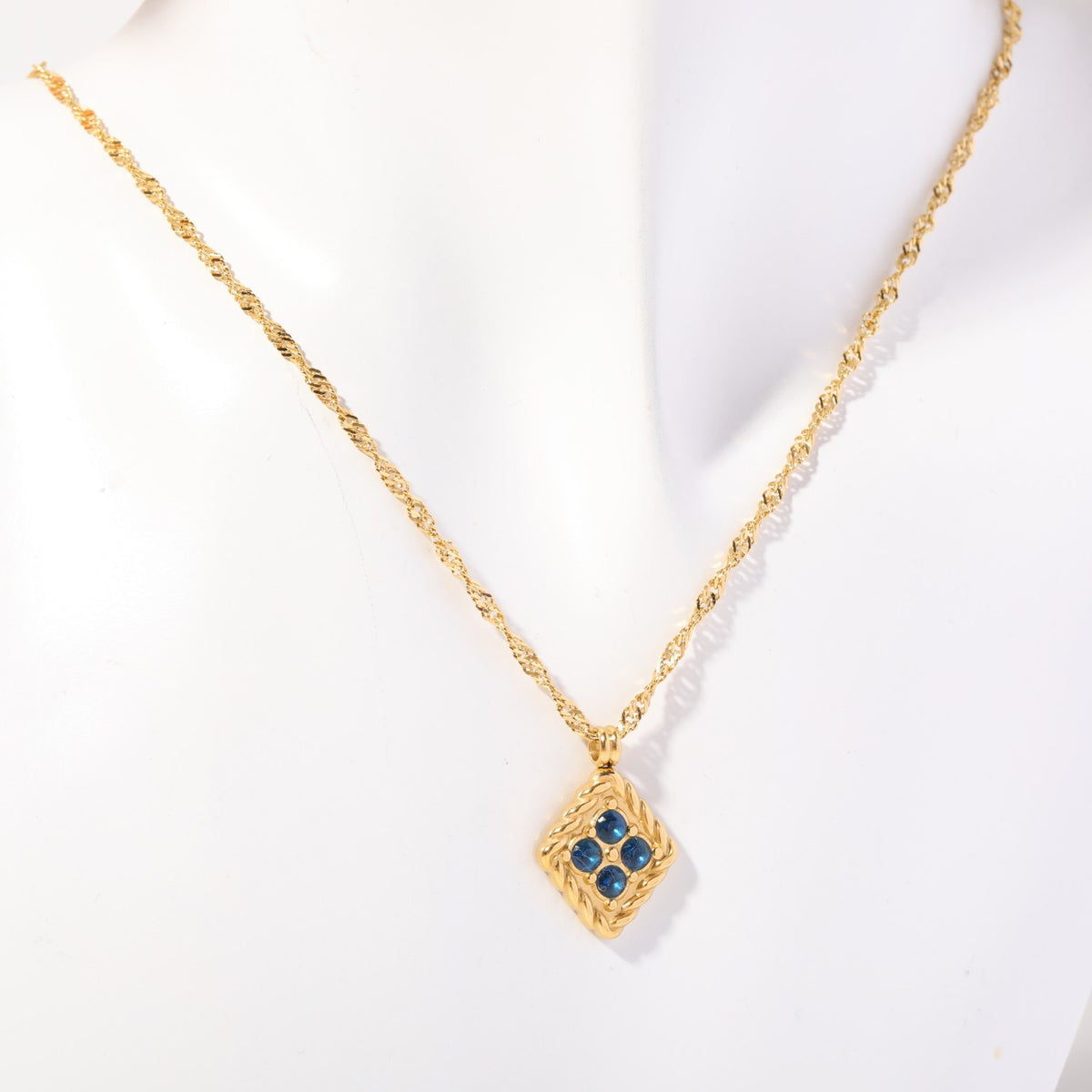 Birthstone necklace with four blue crystals in a twisted gold rope frame, worn on a display bust