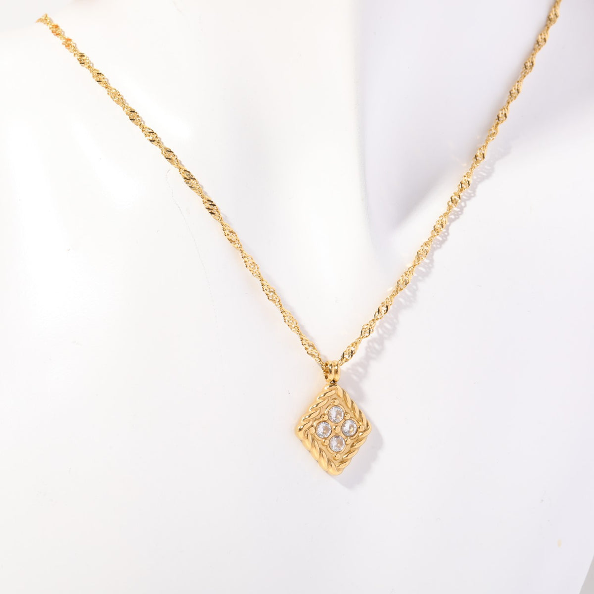 Birthstone necklace with four clear crystals in a twisted gold rope frame, worn on a display bust