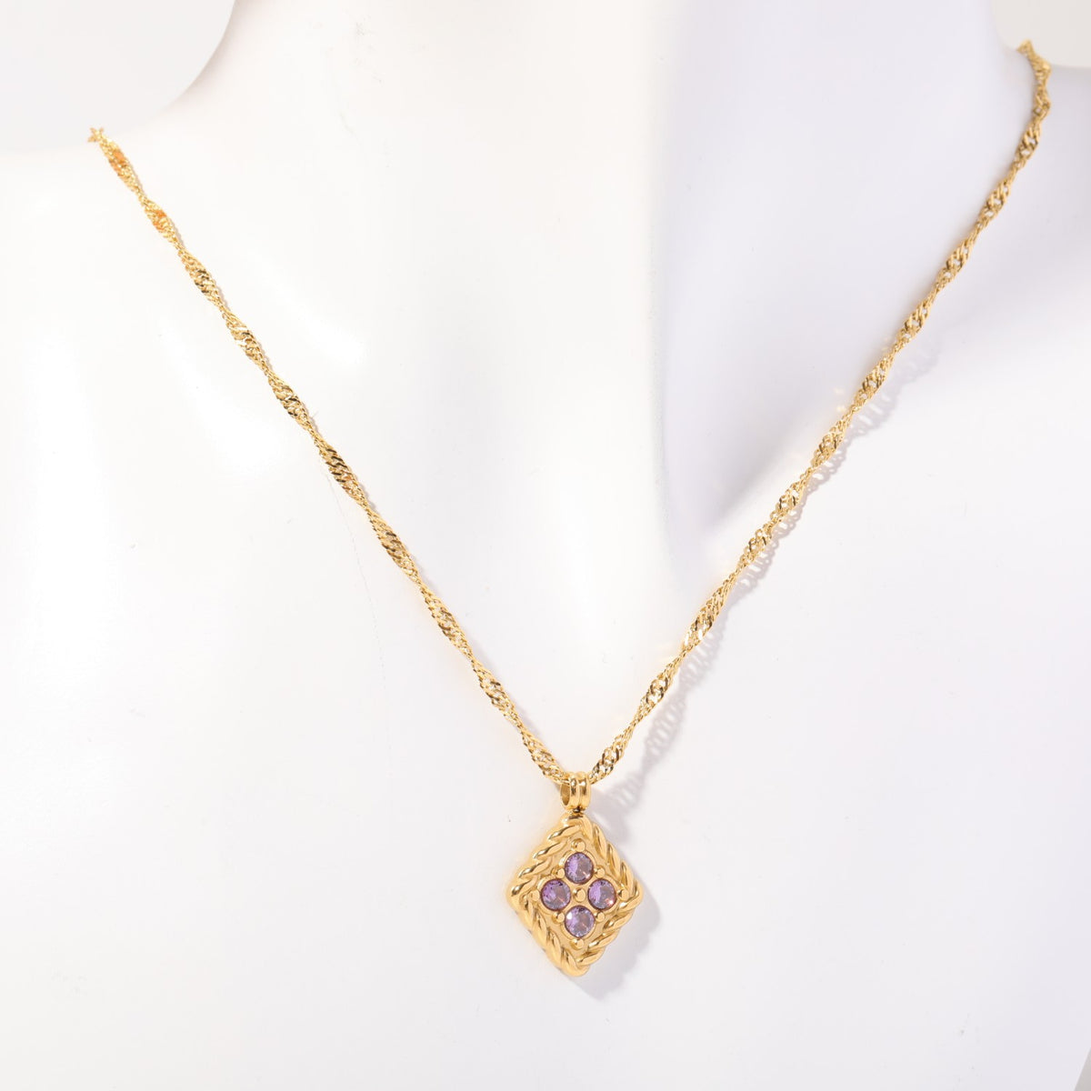 Gold rope-framed birthstone pendant on a fine twist chain, shown on a display bust